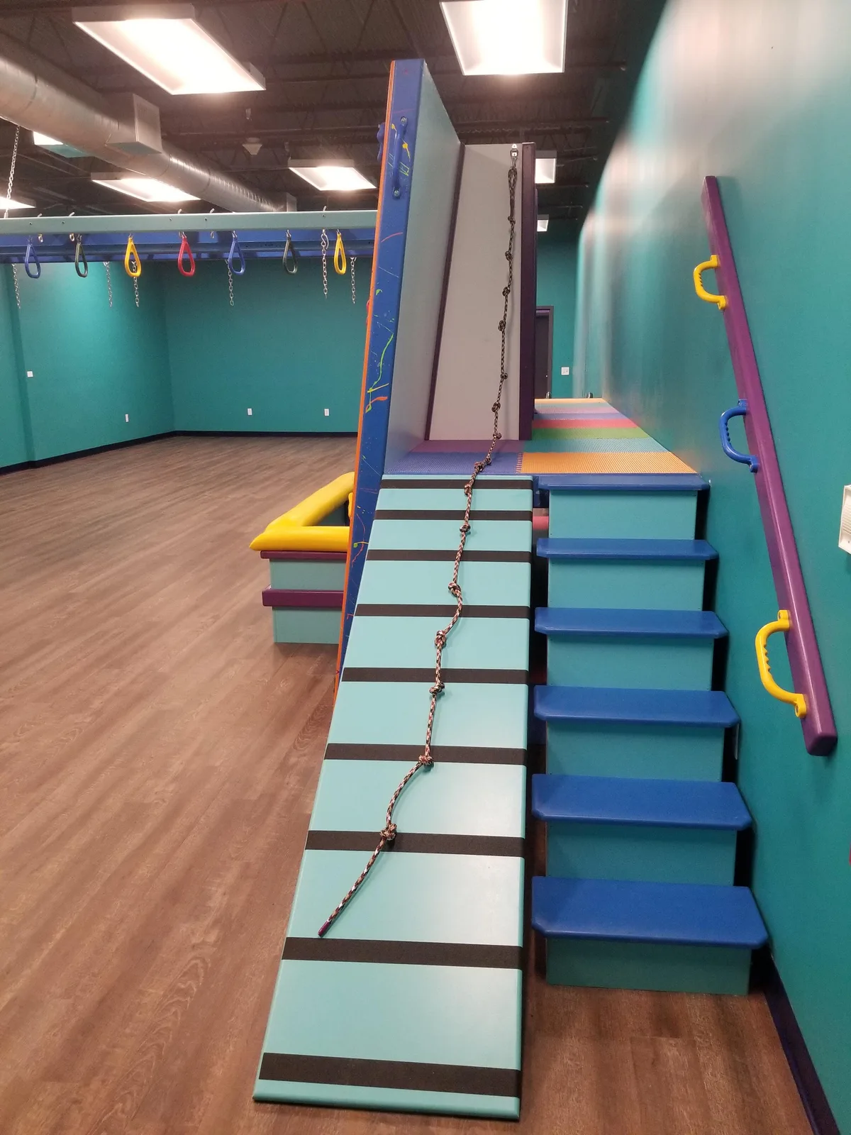 Padded steps and an inclined ramp beneath a colorful overhead frame