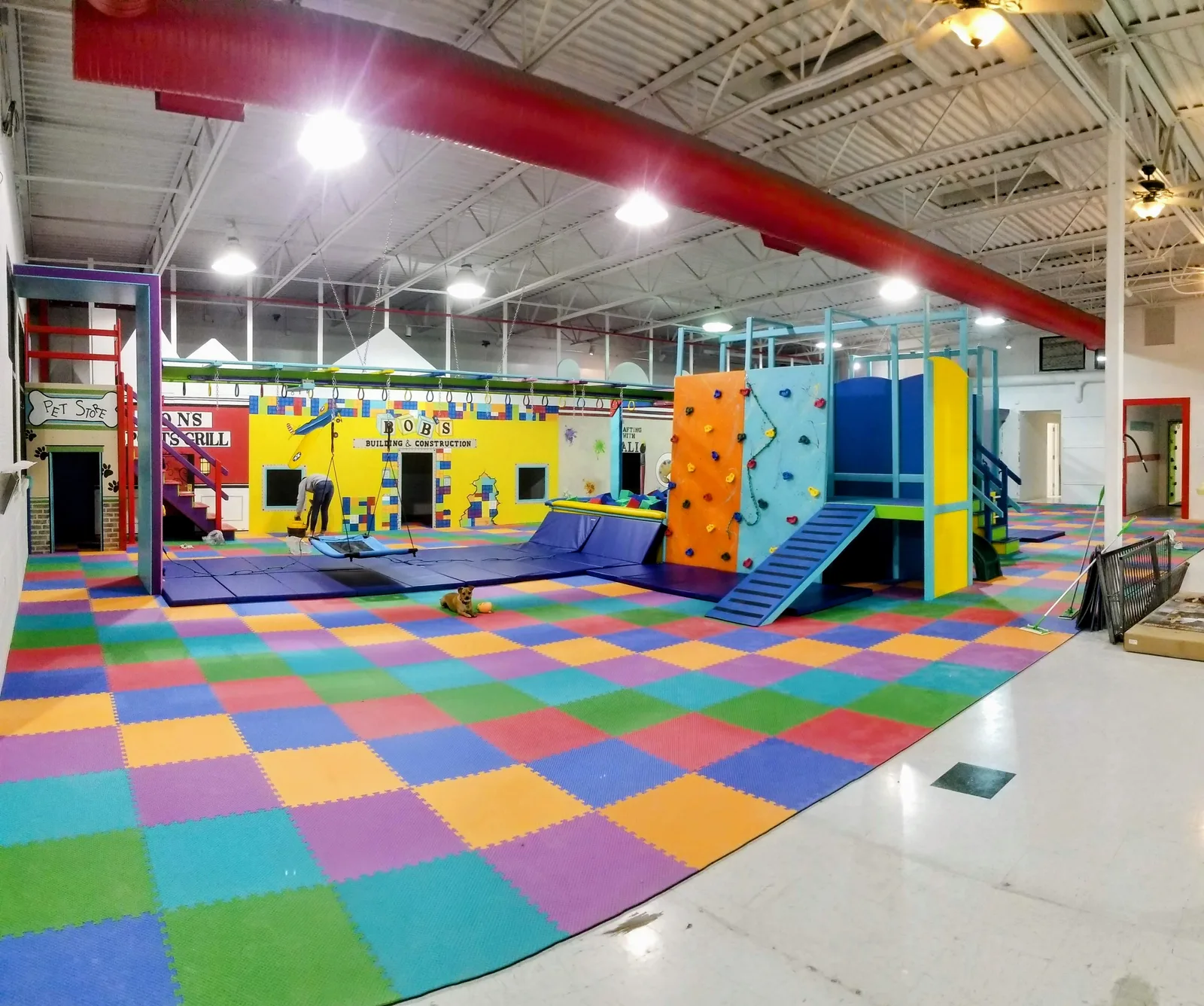 Wide view of a large sensory gym with colorful padded flooring, climbing structures, and open floor space